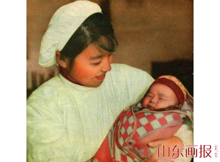 张秋人民公社产院里的助产士魏家珍，抱着亲手接生的婴儿快慰地笑